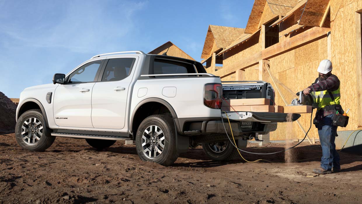 Un Ford Ranger Wildtrak Plug-In Hybrid Ute fournissant une alimentation AC pour les outils sur un chantier urbain avec un commerçant dans le cadre